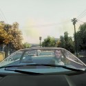 Niko drives a black car through a residential area.